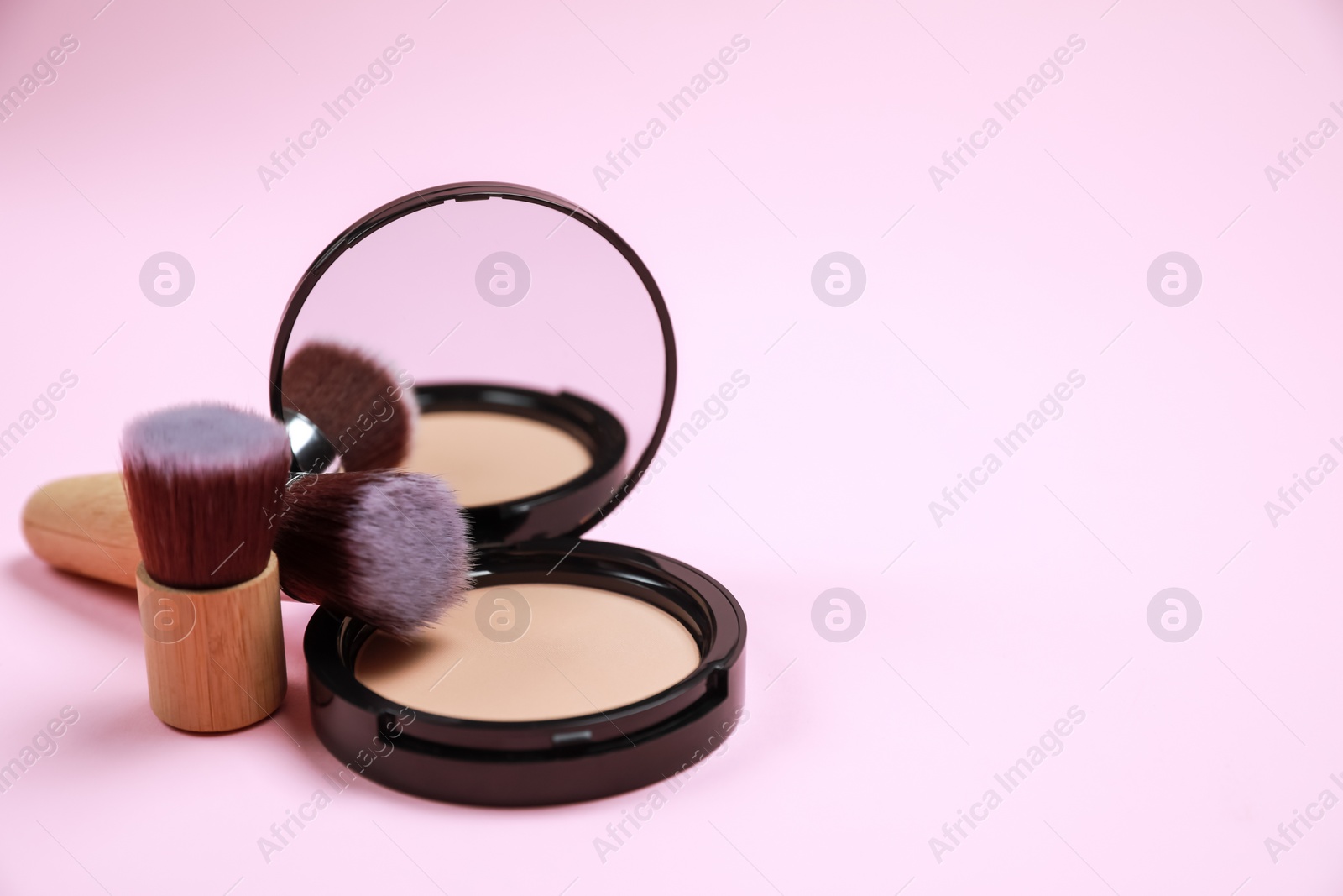 Photo of Face powder and brushes on pink background, space for text
