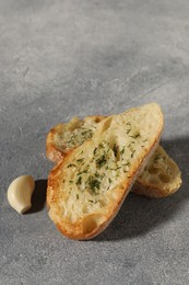 Photo of Tasty baguette with garlic and dill on grey textured table