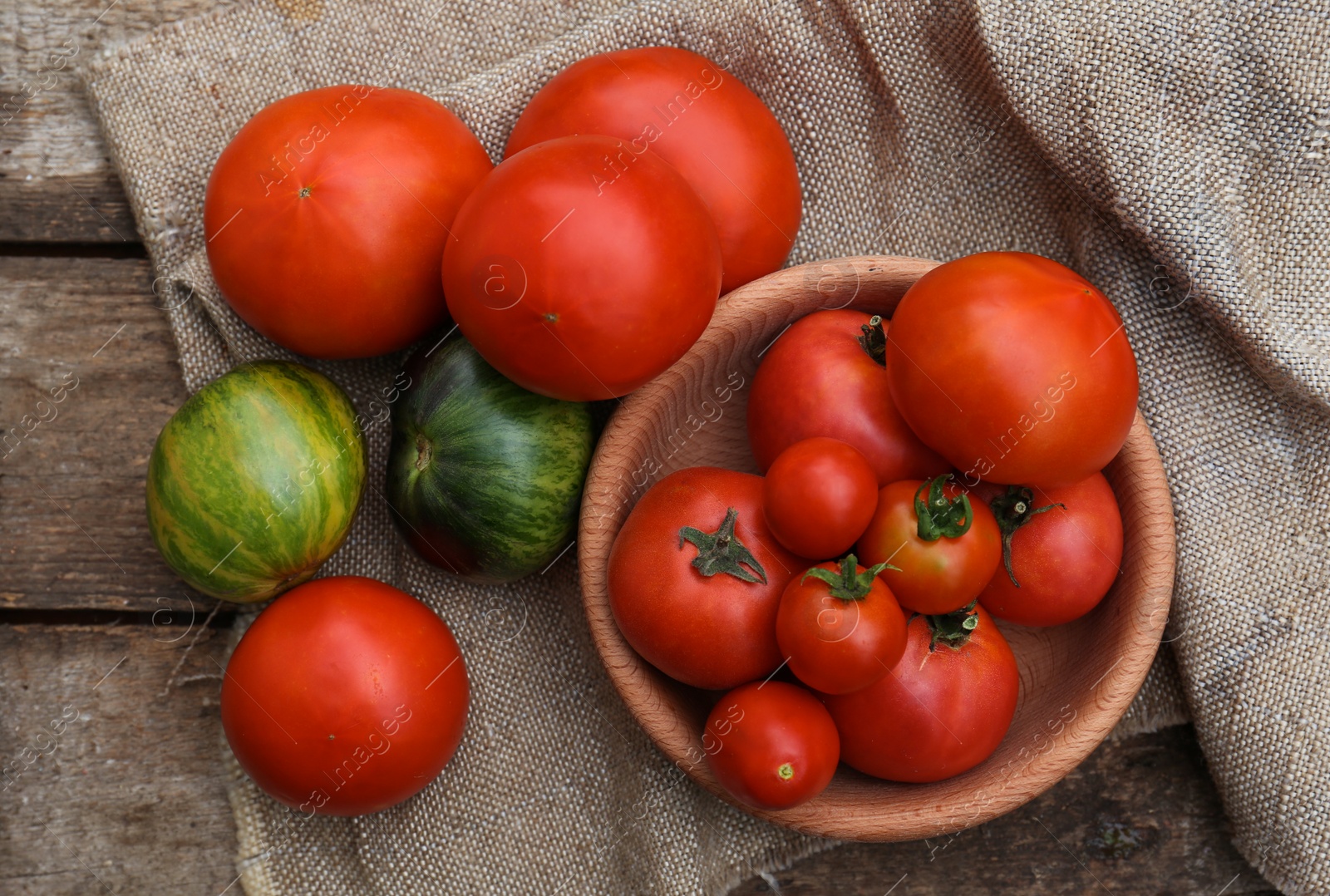 Photo of Many different ripe tomatoes on wooden table, flat lay