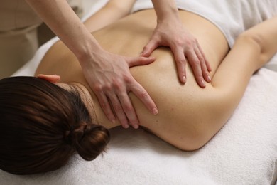 Photo of Woman receiving back massage on couch in spa salon