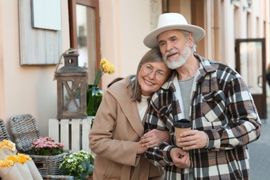 Photo of Affectionate senior couple drinking coffee outdoors, space for text