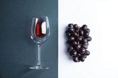 Photo of Fresh ripe juicy grapes and glass with red wine on color background, top view