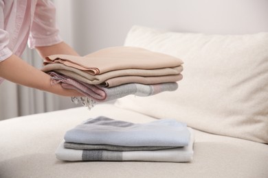 Photo of Woman with folded cashmere clothes indoors, closeup