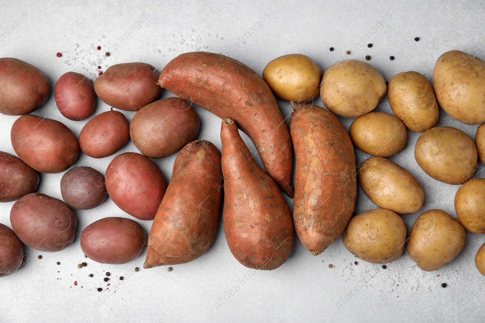 Photo of Different types of fresh potatoes on light gray table, flat lay