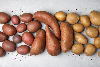 Photo of Different types of fresh potatoes on light gray table, flat lay