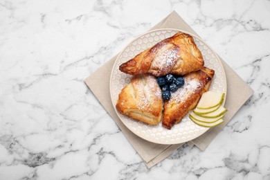 Photo of Fresh tasty puff pastry with sugar powder, pear and blueberries served on white marble table, top view. Space for text