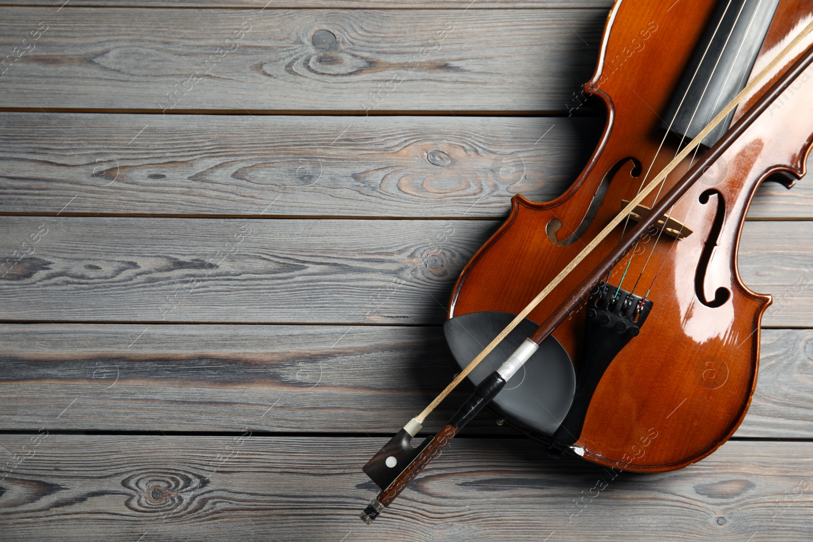 Photo of Classic violin and bow on wooden background, top view. Space for text