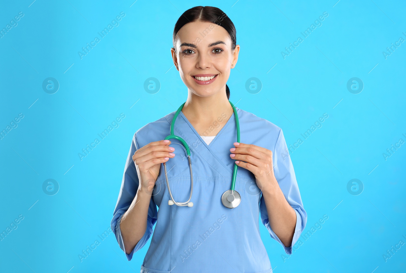 Photo of Portrait of young doctor with stethoscope on blue background