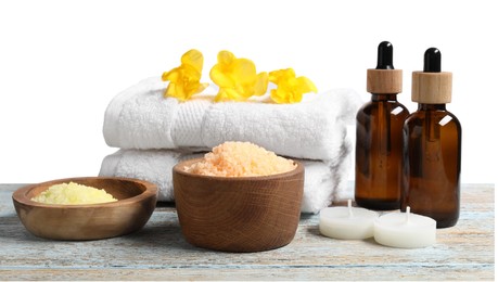 Photo of Natural sea salt in bowls and other spa supplies on wooden table against white background