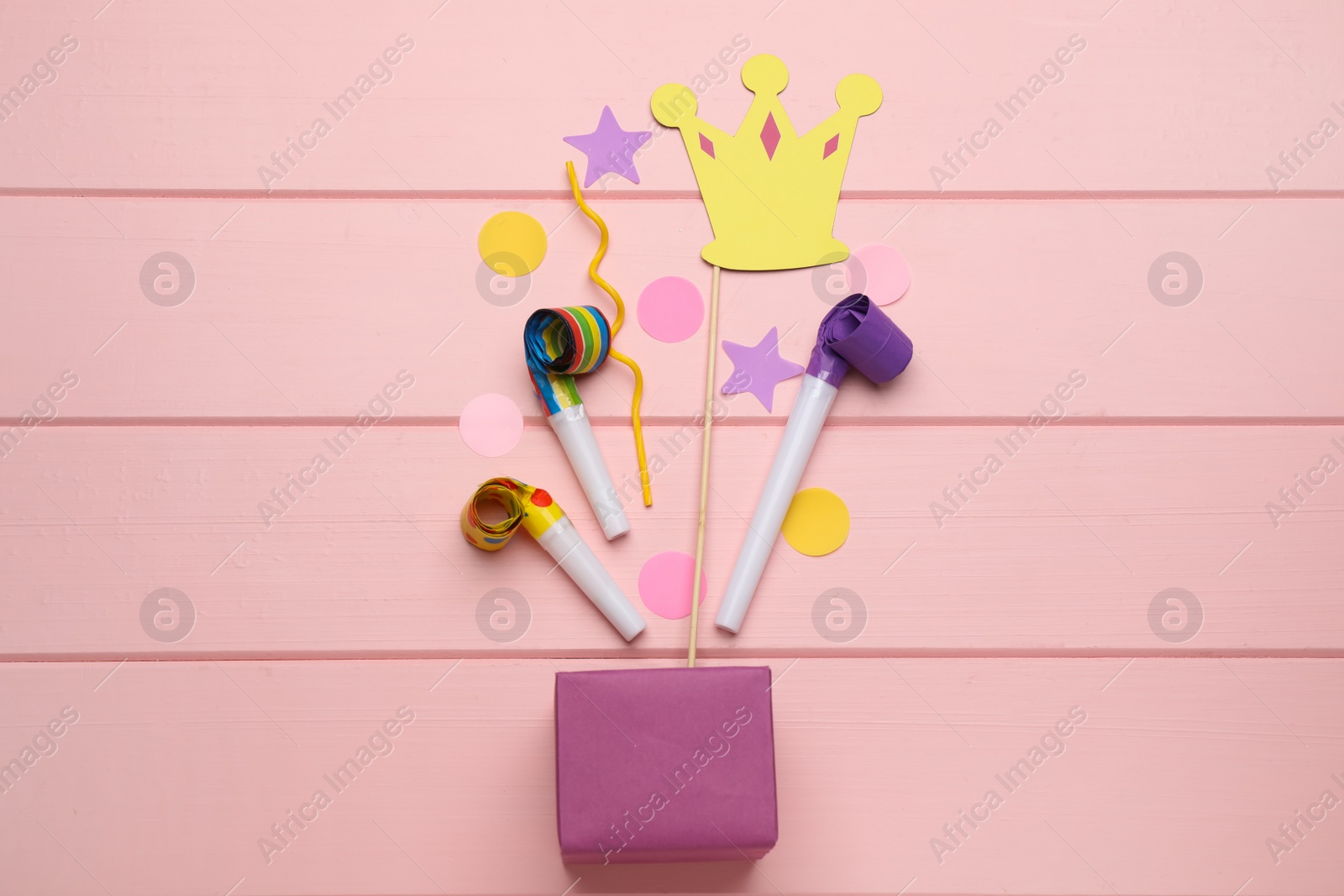 Photo of Flat lay composition with party items and box on pink wooden table