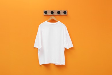 Photo of Hanger with white T-shirt on orange wall