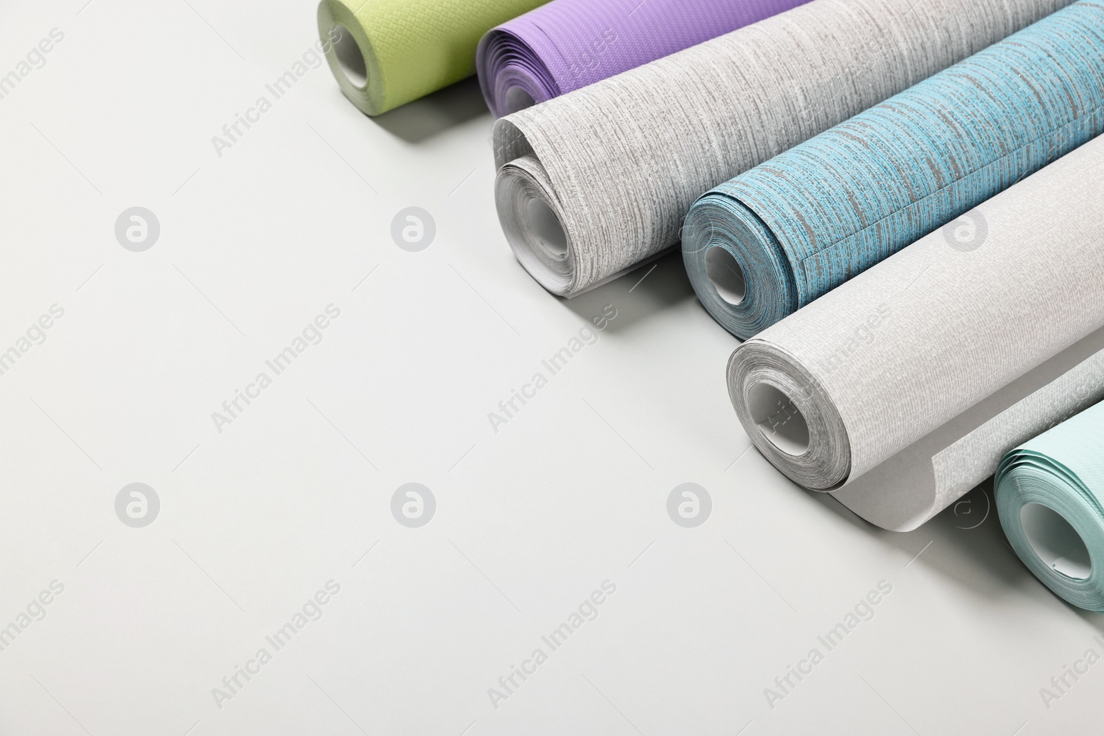 Photo of Different wallpaper rolls on light background. Space for text