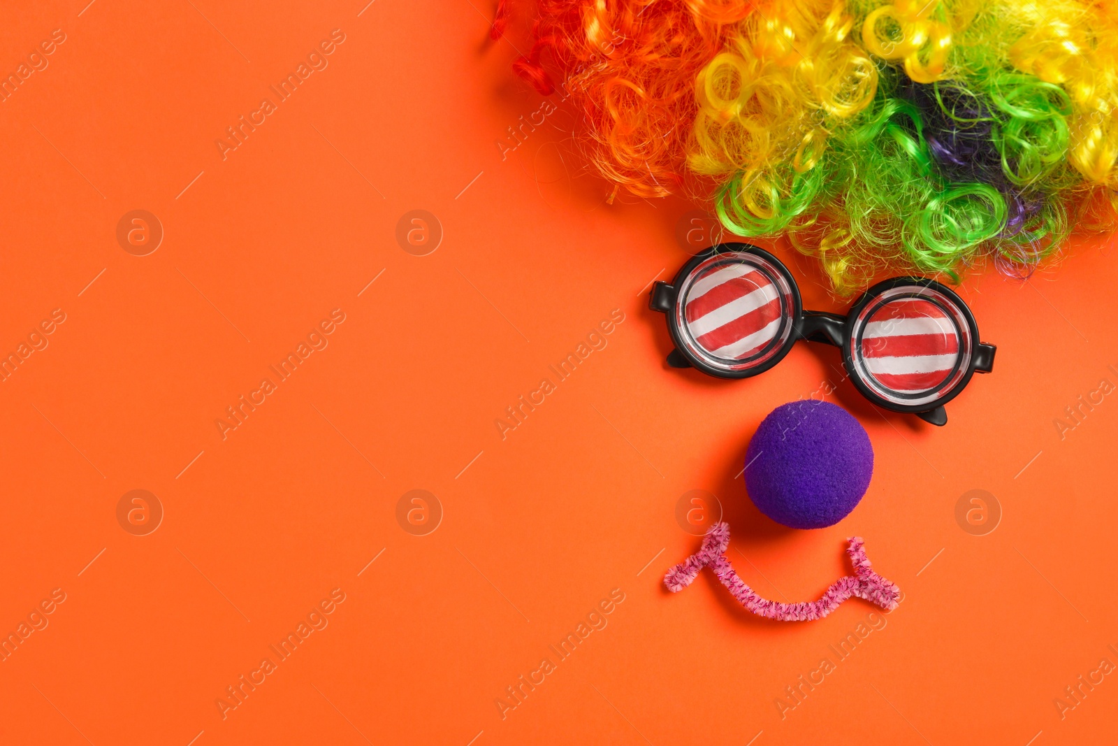 Photo of Funny face made with clown's accessories on red background, flat lay. Space for text