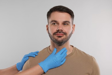 Photo of Endocrinologist examining thyroid gland of patient on light grey background, closeup
