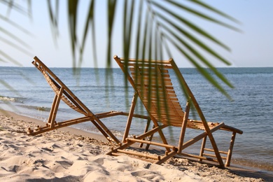 Sandy beach with empty wooden sunbeds on sunny day