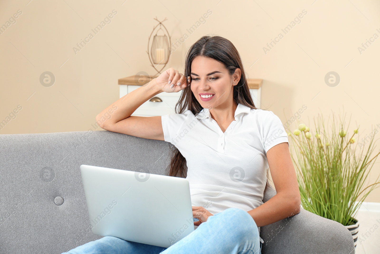 Photo of Beautiful woman with laptop sitting on sofa at home