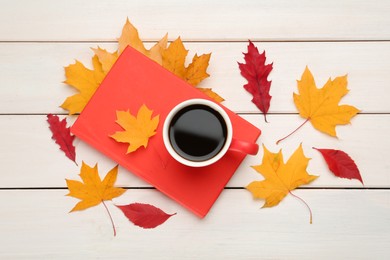 Cup of hot coffee, book and autumn leaves on white wooden table, flat lay