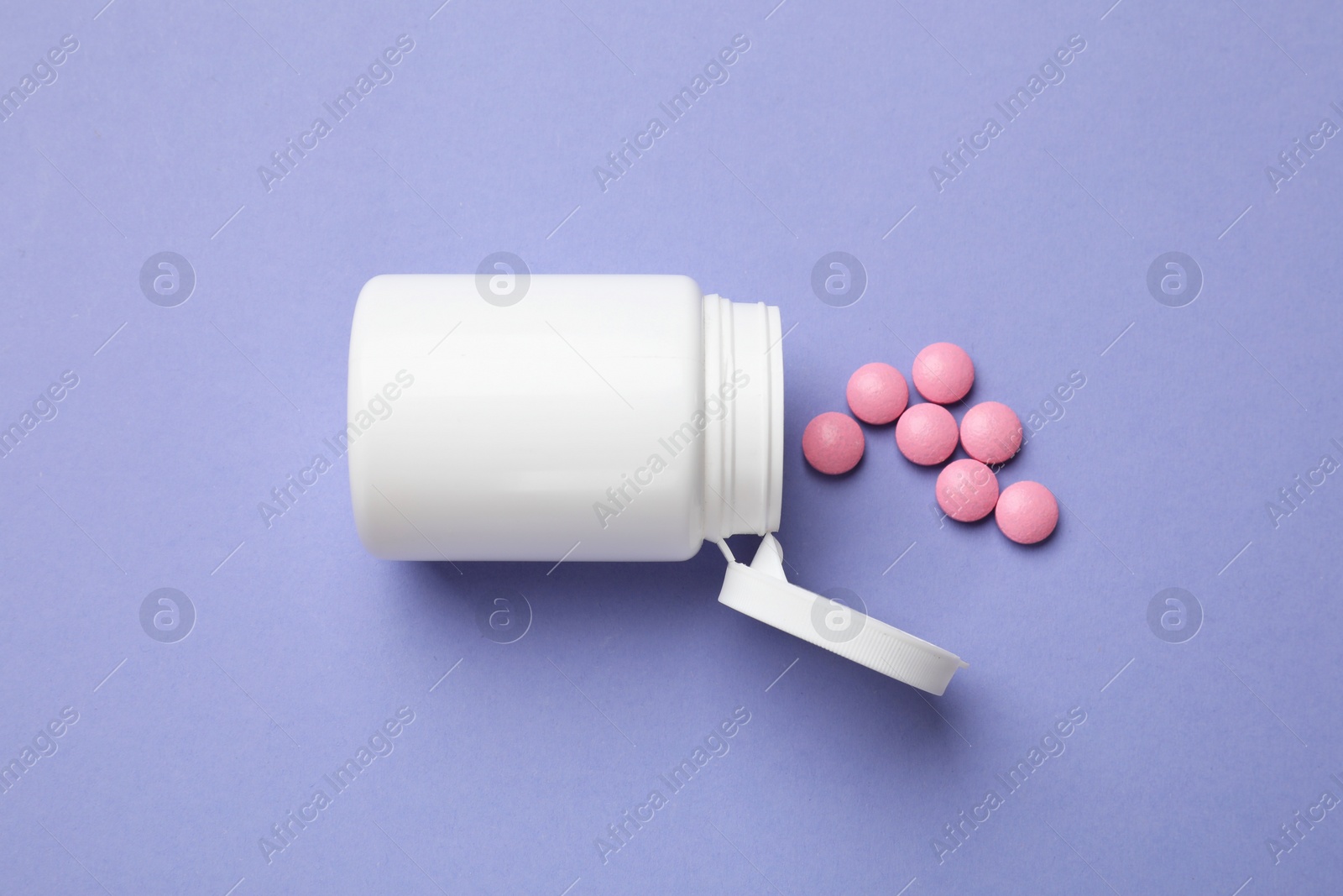 Photo of White bottle and vitamin pills on violet background, top view