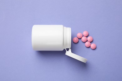 Photo of White bottle and vitamin pills on violet background, top view