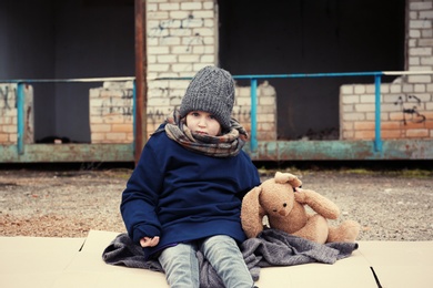 Photo of Poor little girl with toy rabbit on dirty street