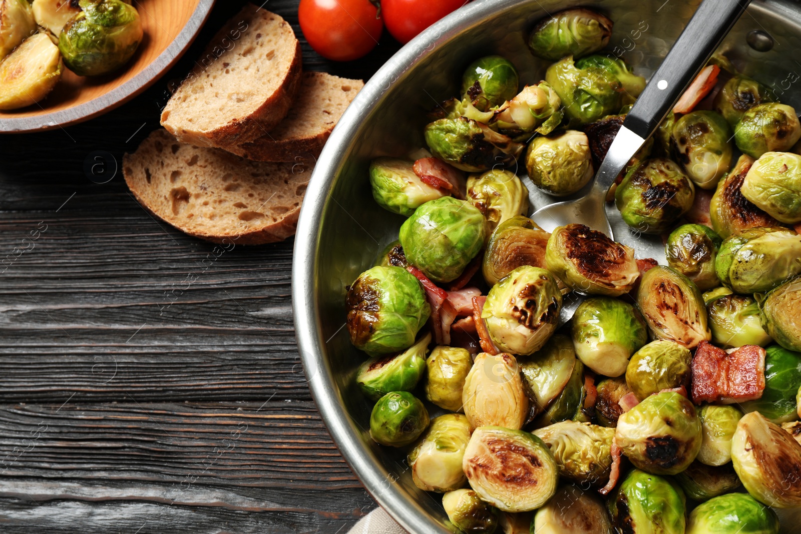 Photo of Delicious Brussels sprouts with bacon on grey wooden table, flat lay