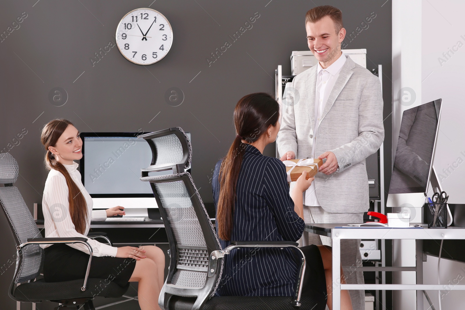 Photo of Man presenting gift to his colleague in office
