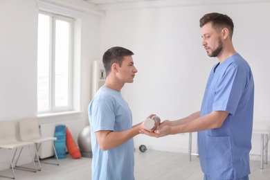 Photo of Physiotherapist working with male patient in clinic