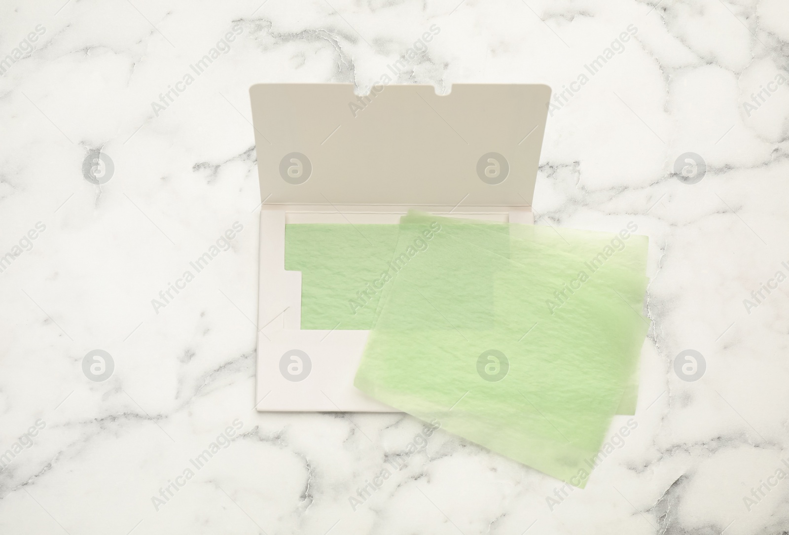 Photo of Facial oil blotting tissues on white marble table, flat lay. Mattifying wipes