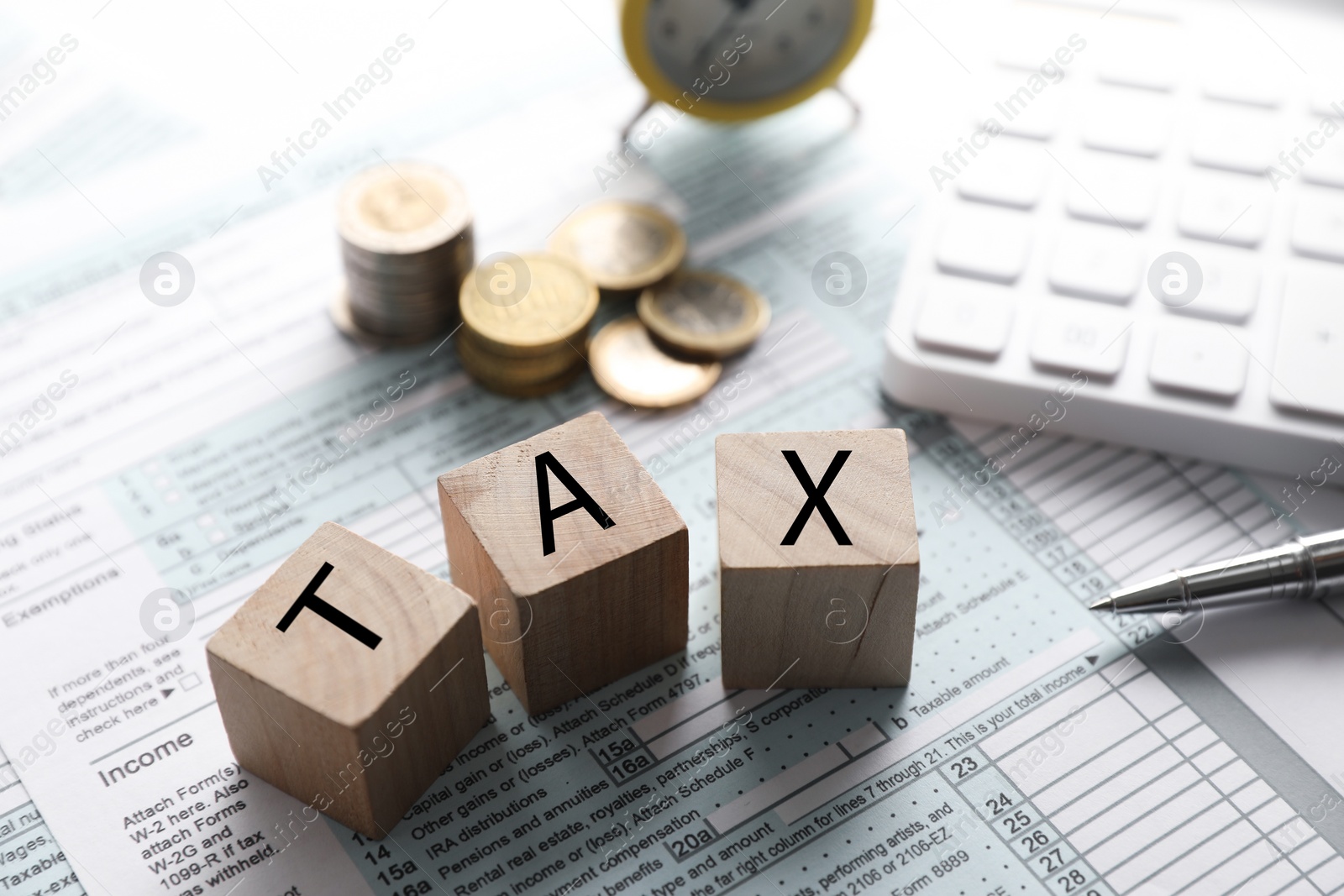 Photo of Wooden cubes with word Tax, calculator, coins and pen on document, closeup