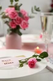 Photo of Romantic table setting. Plate with pink rose on table, closeup
