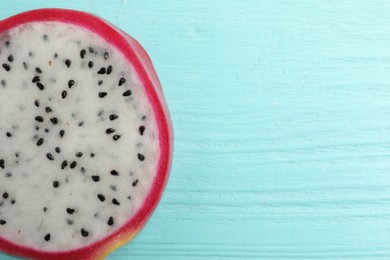 Photo of Cut dragon fruit (pitahaya) on light blue wooden table, top view. Space for text