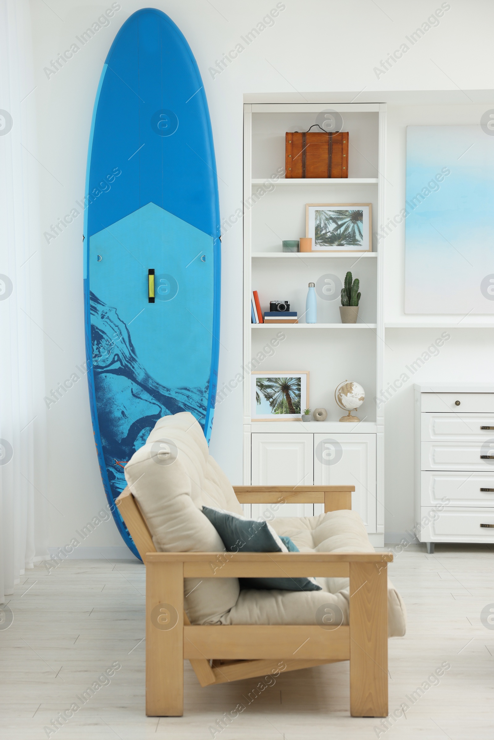 Photo of SUP board and modern furniture in stylish living room. Interior design
