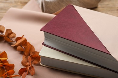 Photo of Furoshiki technique. Books, dry branches and beige fabric on table, closeup