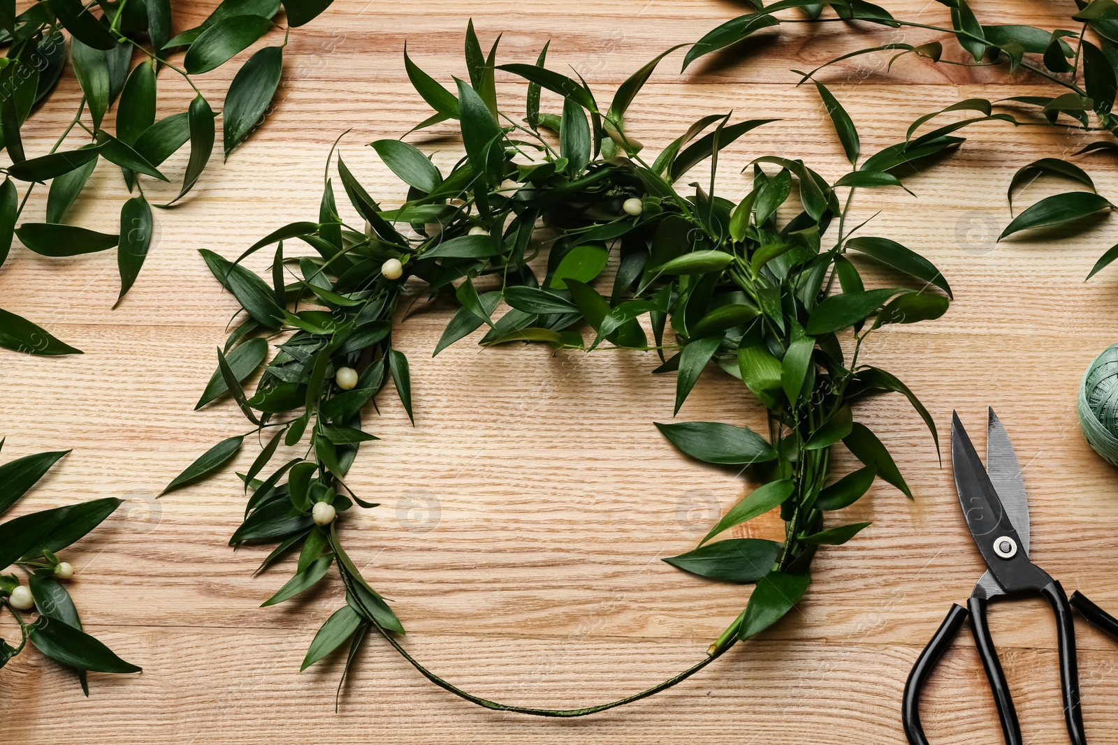 Photo of Unfinished mistletoe wreath and florist supplies on wooden table, flat lay. Traditional Christmas decor