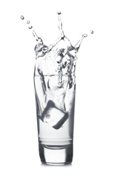 Ice cube falling into shot glass of vodka on white background