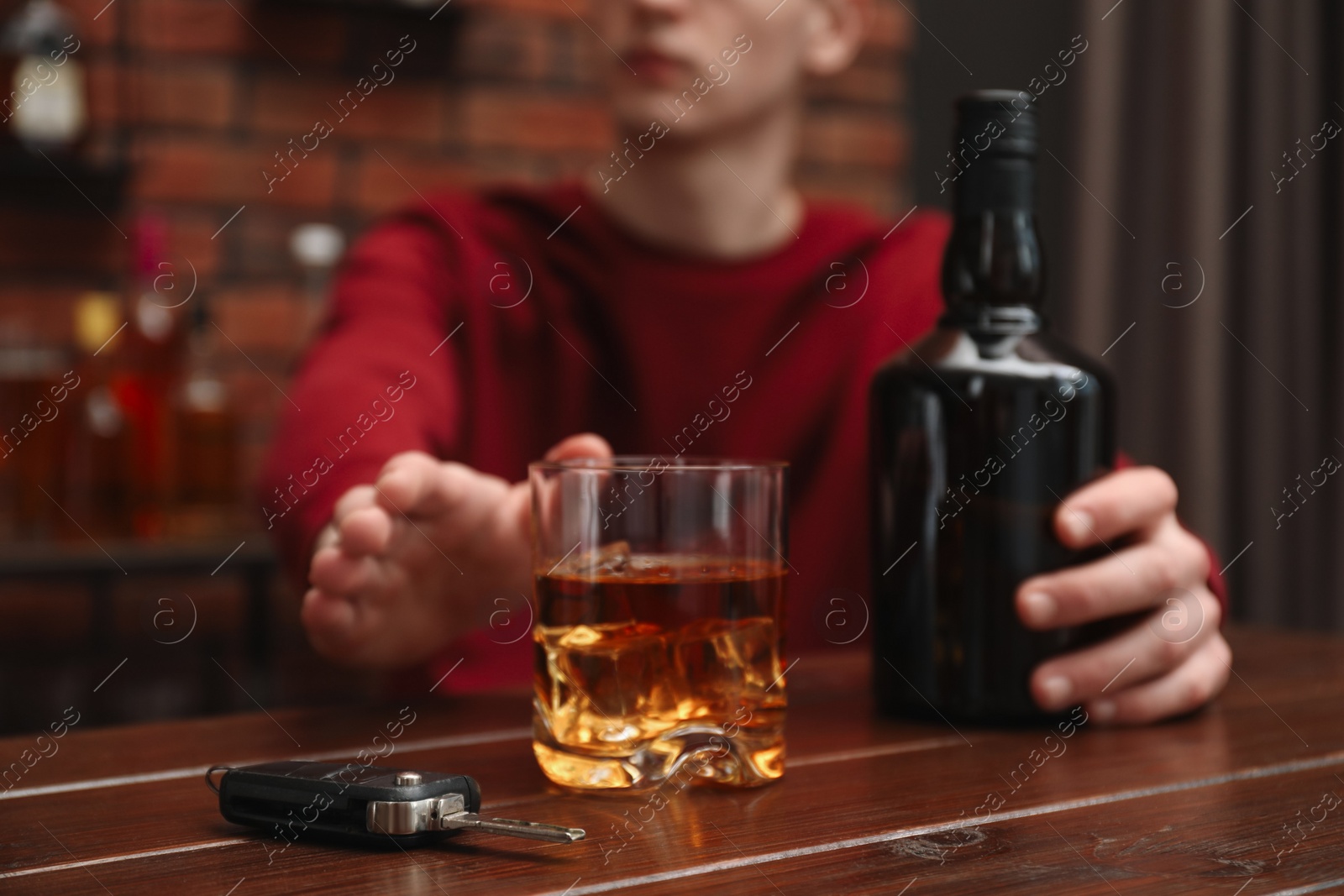 Photo of Man reaching for alcoholic drink at table with car keys, closeup. Don't drink and drive concept