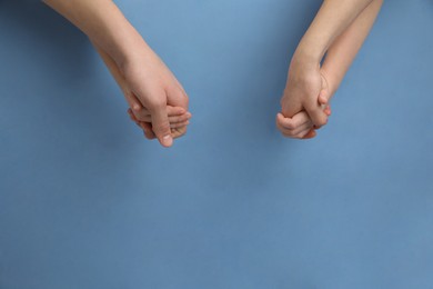 Photo of Happy family holding hands on light blue background, top view. Space for text