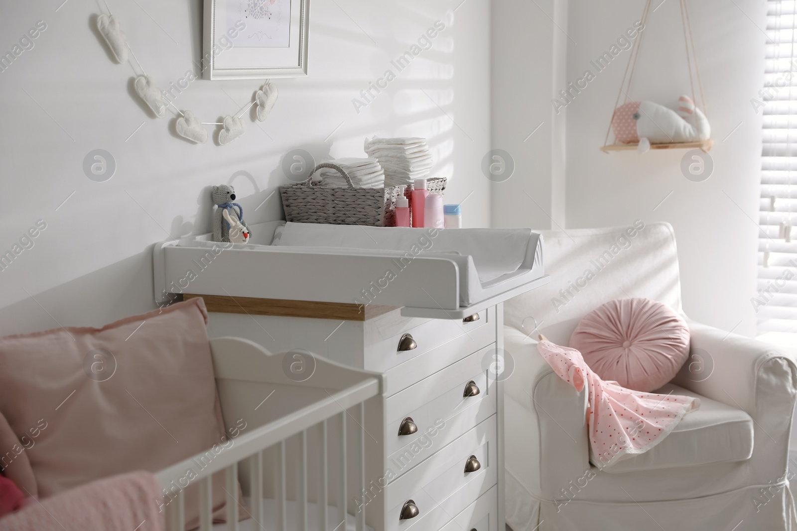 Photo of Chest of drawers with changing tray and pad in baby room. Interior design