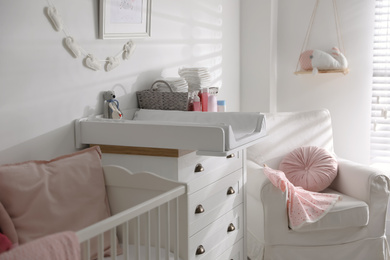 Photo of Chest of drawers with changing tray and pad in baby room. Interior design