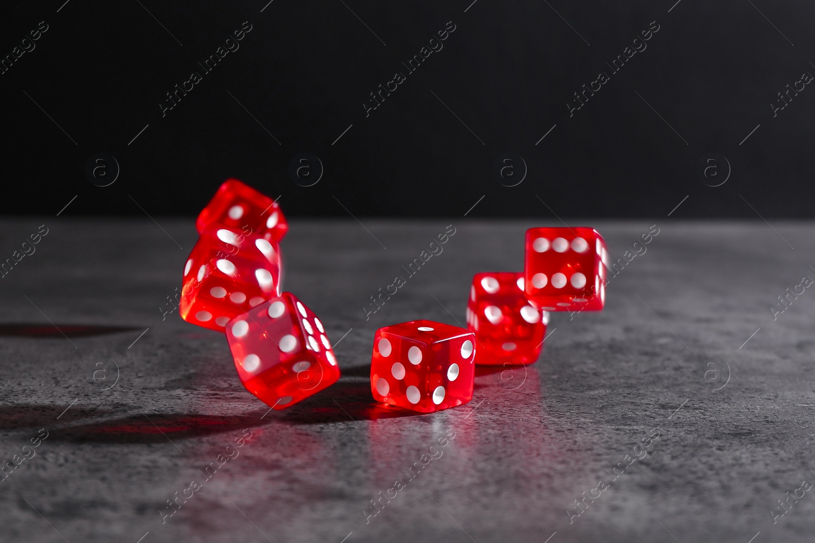 Photo of Many red game dices falling on grey textured table. Space for text