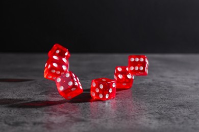 Photo of Many red game dices falling on grey textured table. Space for text