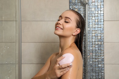 Beautiful young woman taking shower with soap in bathroom. Space for text