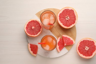 Tasty freshly made grapefruit juice and fruits on white wooden table, top view