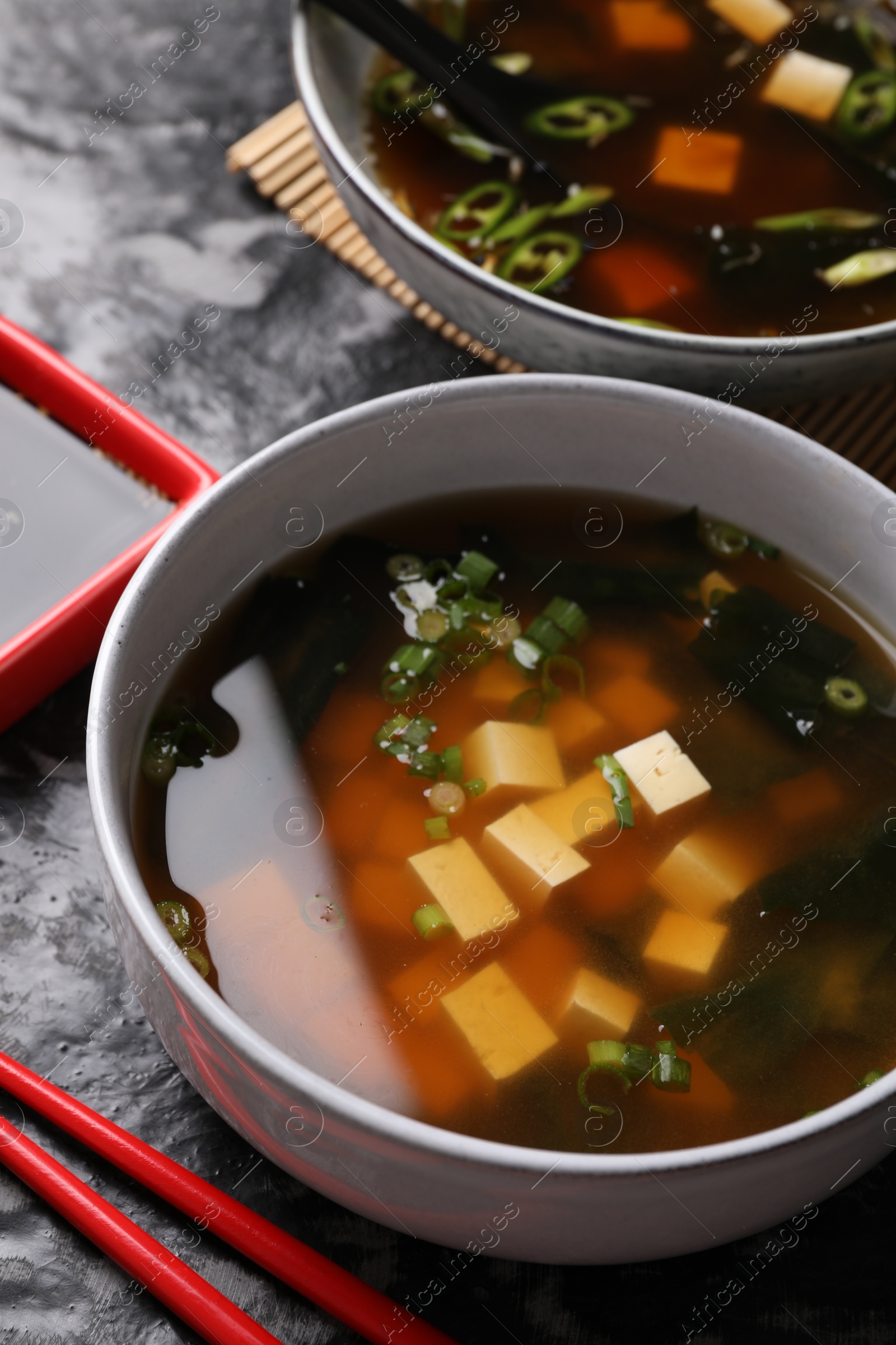 Photo of Delicious miso soup with tofu served on black textured table, above view