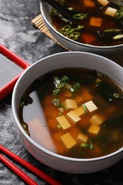 Delicious miso soup with tofu served on black textured table, above view