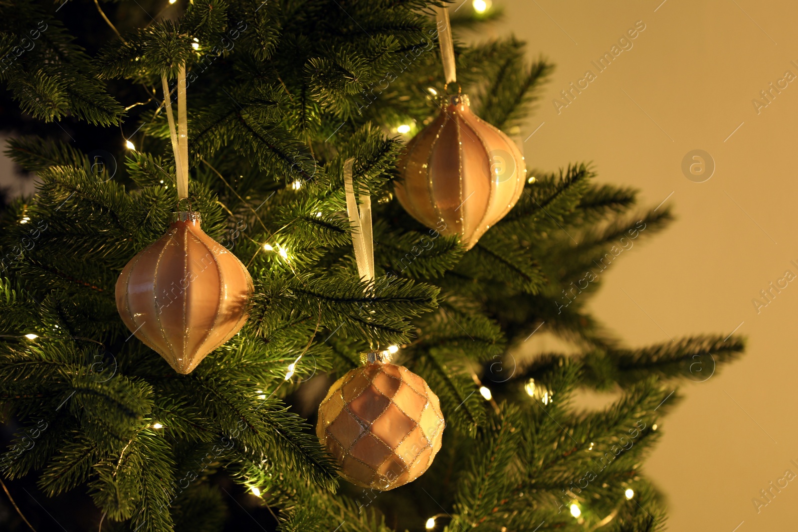 Photo of Christmas tree decorated with holiday baubles and fairy lights, closeup
