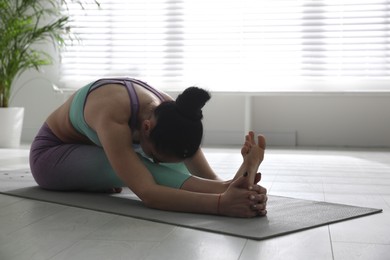 Photo of Woman practicing head to knee forward bend asana in yoga studio. Janu sirsasana pose