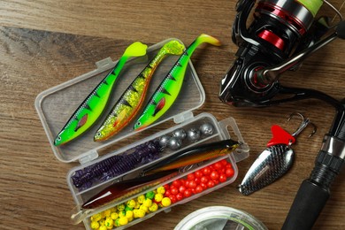 Photo of Fishing rod with spinning reel and baits on wooden background, flat lay