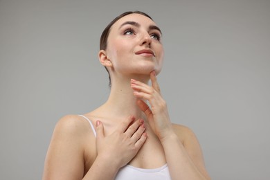 Photo of Beautiful woman touching her chin on grey background