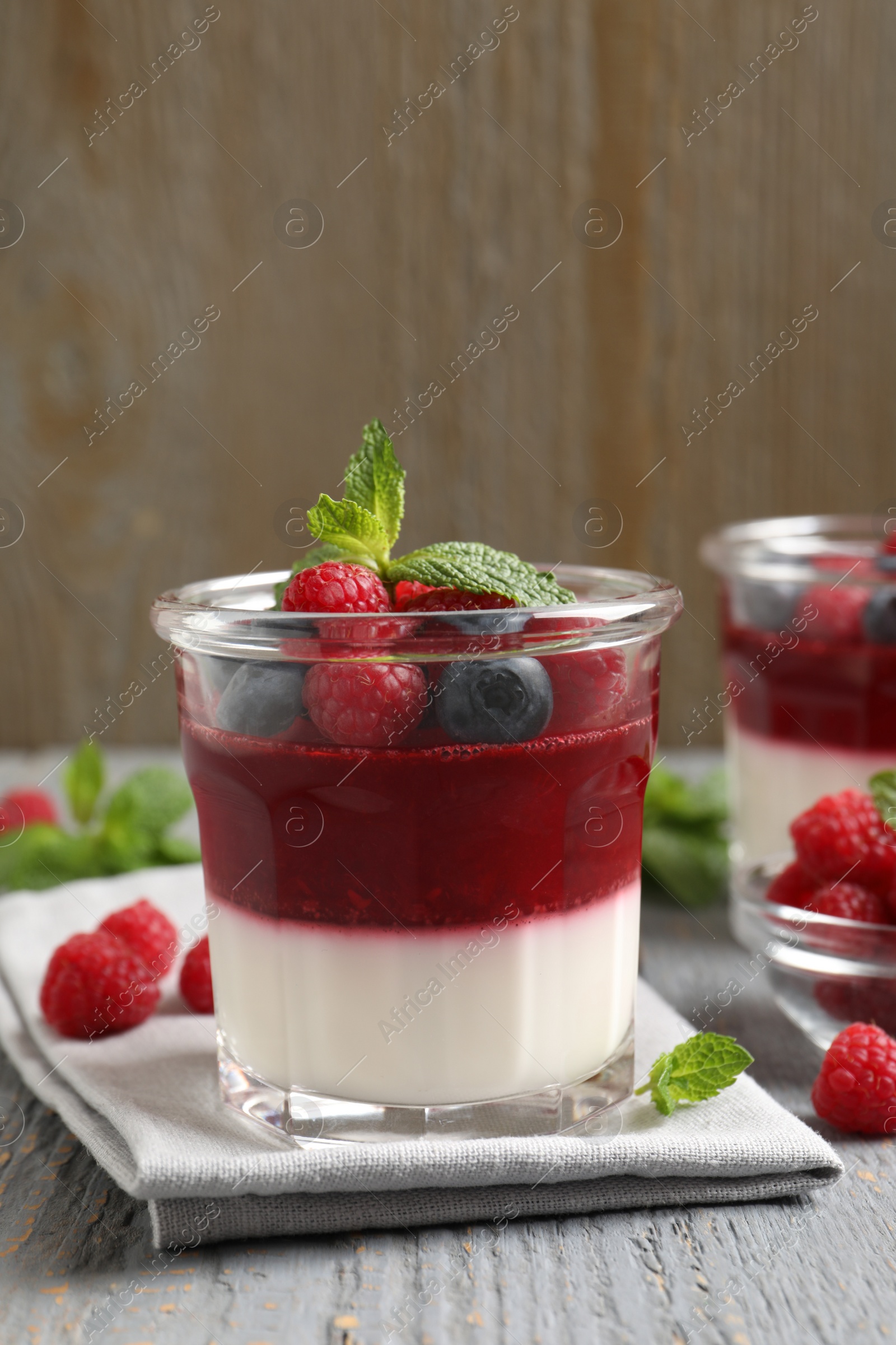 Photo of Delicious panna cotta with berries on grey wooden table